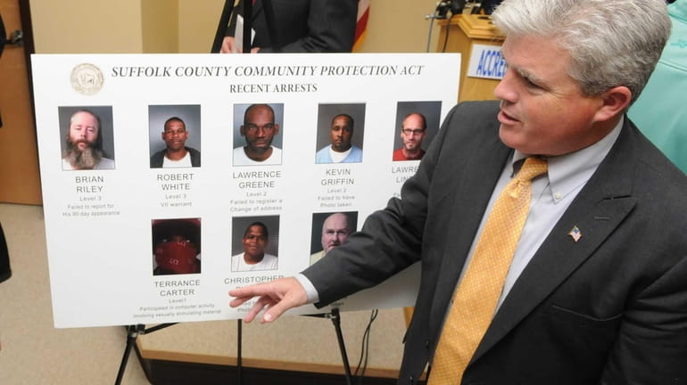 Suffolk County Executive Steve Bellone looks at the mugshots of...