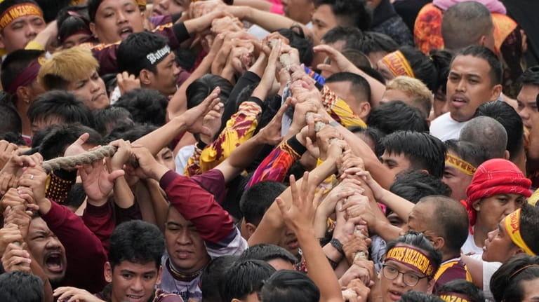 Devotees grab the rope as they pull the glass-covered cart...