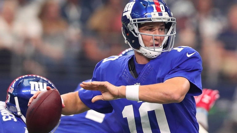 Eli Manning of the New York Giants drops back to...
