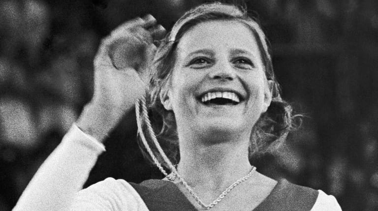 USSR's Olga Korbut holds up her gold medal in the gymnastics...