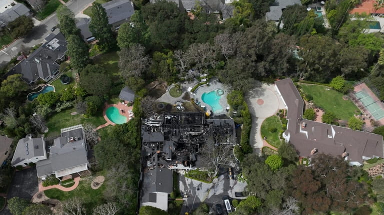 An aerial view shows a fire-damaged property, which appears to...