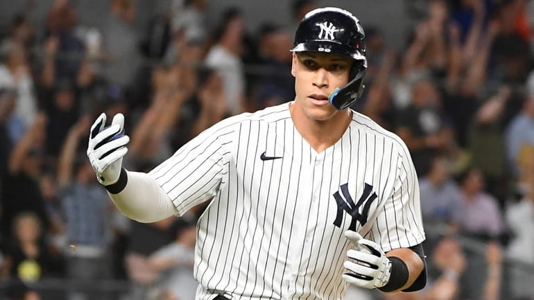 The Yankees' Aaron Judge gestures to the dugout as he...