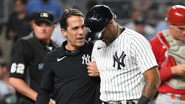 The Yankees' Aaron Hicks is assisted off the field by...