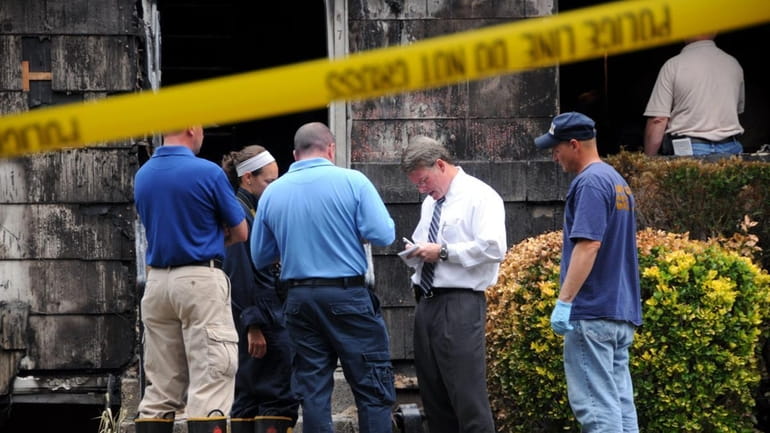 Investigators comb a Central Islip house where three bodies were...