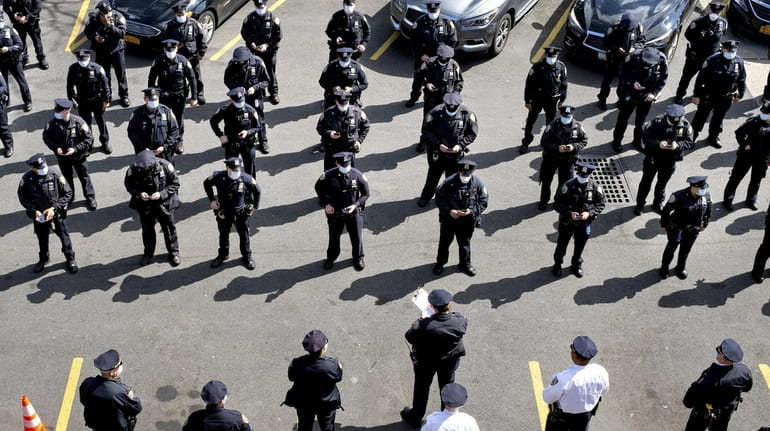 Wearing protective masks, NYPD officers attend roll call Wednesday at the...