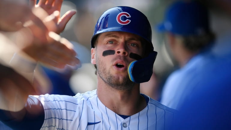 Chicago Cubs' Nico Hoerner celebrates in the dugout with teammates...