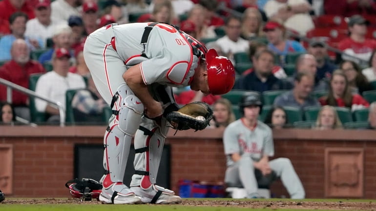 Philadelphia Phillies catcher J.T. Realmuto doubles over after being injured...