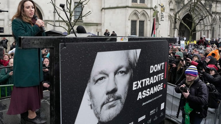 Stella Assange, wife of Julian Assange, speaks besides a poster...