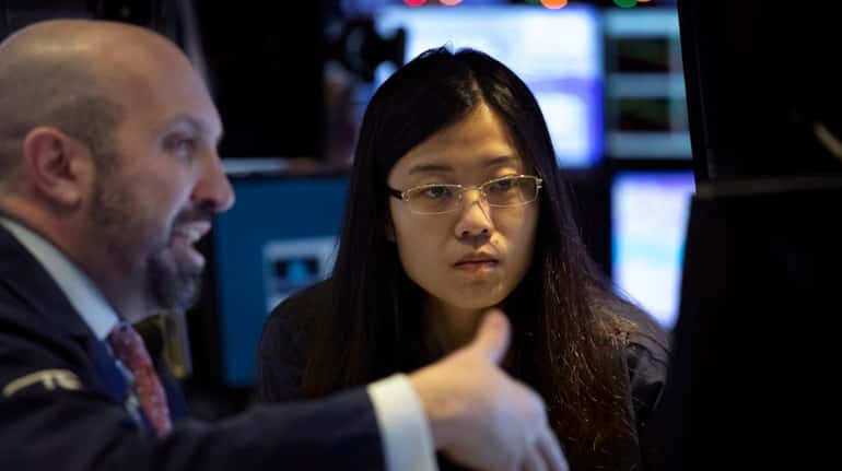 Stock traders James Denaro, left, and Vera Liu follow stock...