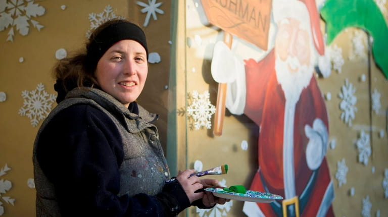 MW Designs owner Marianne Wegener paints a holiday-themed window at...
