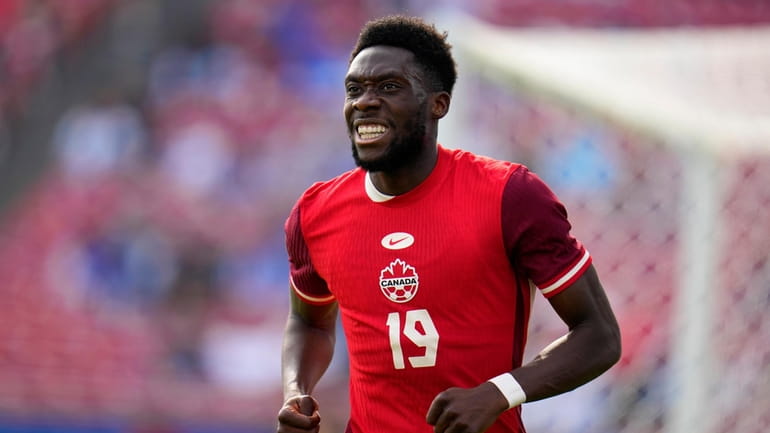 Canada forward Alphonso Davies (19) jogs up field after taking...
