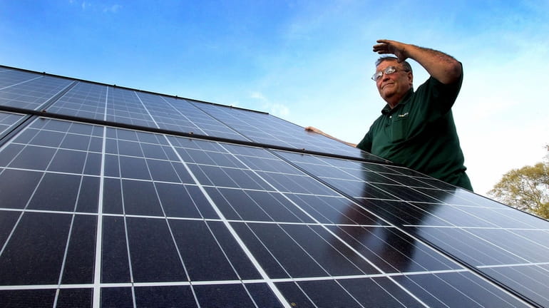 Gary Minnick, owner of Go Solar Incorporated in Aquebogue, examines...