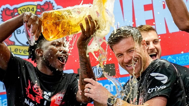Leverkusen's head coach Xabi Alonso , centre, is sprayed with...