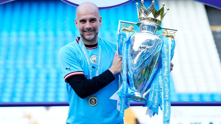 Manchester City's head coach Pep Guardiola poses with the trophy...