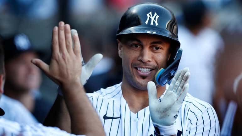 Yankees designated hitter Giancarlo Stanton celebrates in the dugout after hitting...