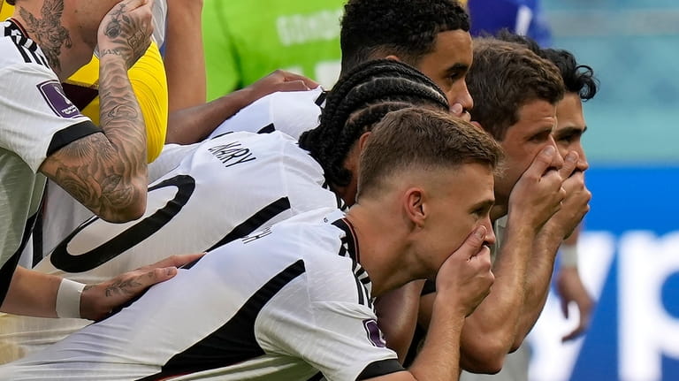 Germany players put their hands on their mouths as they...