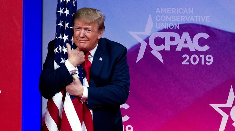 President Donald Trump hugs the American flag as he arrives...