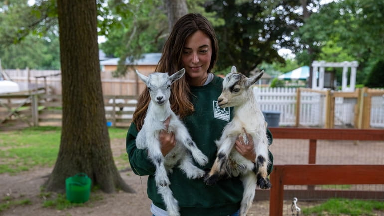 Zookeeper Chela Novak holds two goats at Long Island Game...