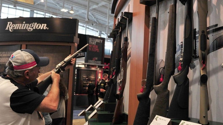 A convention attendee looks at a Remington bolt action rifle...