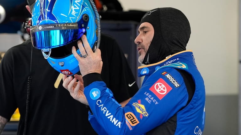 Jimmie Johnson prepares to put on his helmet during a...