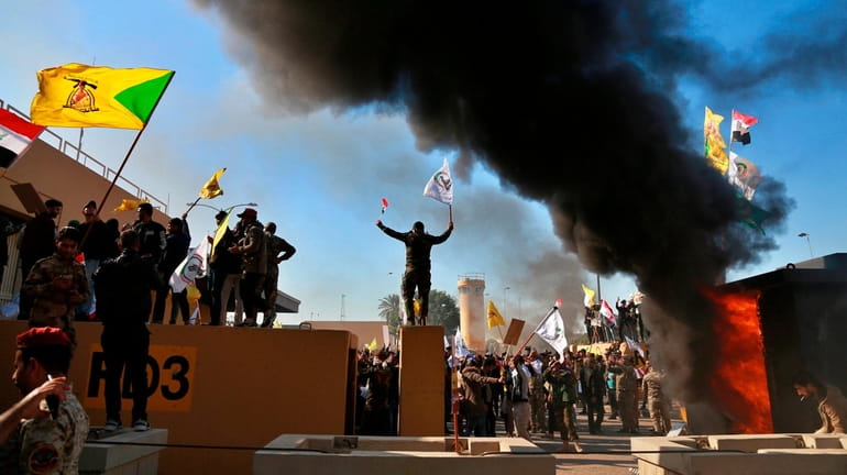 Supporters of an Iran-backed Iraqi Shia militia burn property in...
