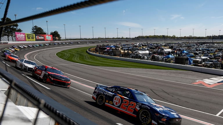 ]Joey Logano (22) leads a pack of cars through Turn...