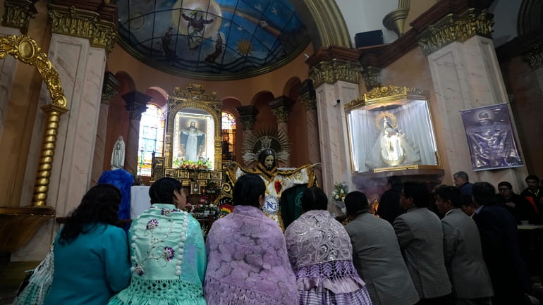 Devotees pray after dressing the statue of "Jesus del Gran...