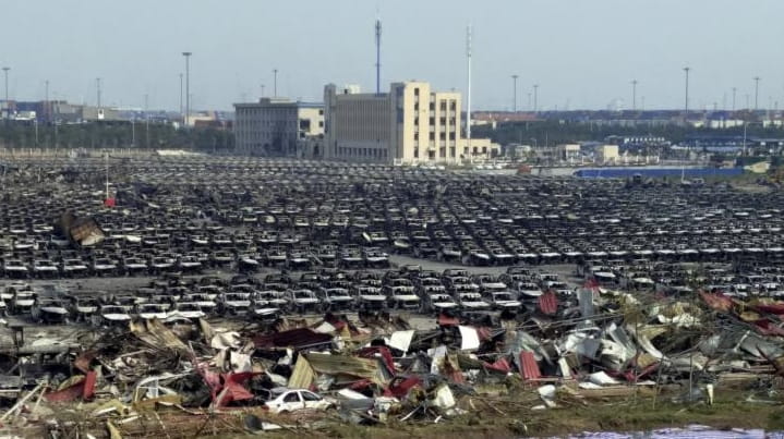 Charred remains of new cars are seen in a parking...