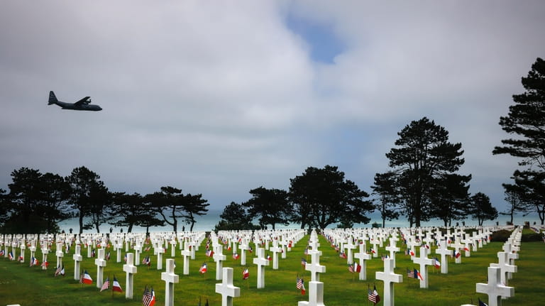 A plane flies over the American Cemetery in Colleville-sur-Mer, Normandy,...