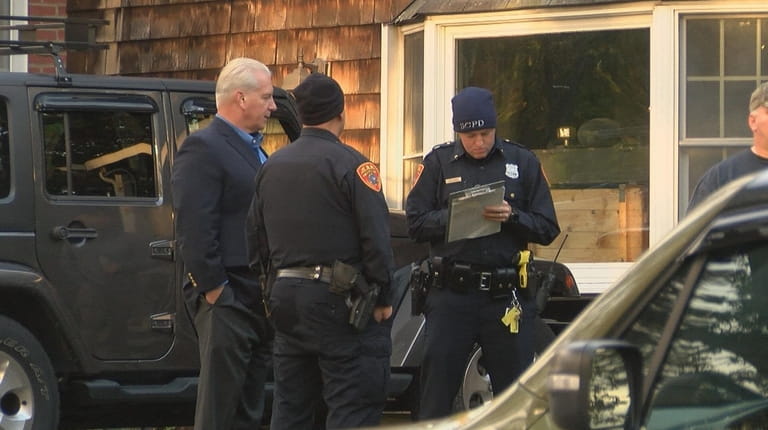 Investigators confer outside the Carrolls' Olive Street home Wednesday afternoon.
