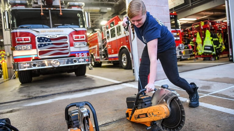 Firefighter EMT Jessica Leeb starts a saw in front of...