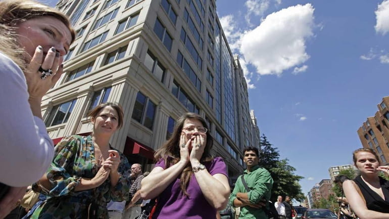 Office workers gather on the sidewalk in downtown Washington, Tuesday...