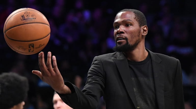 The Nets' Kevin Durant tosses the ball during a timeout against...
