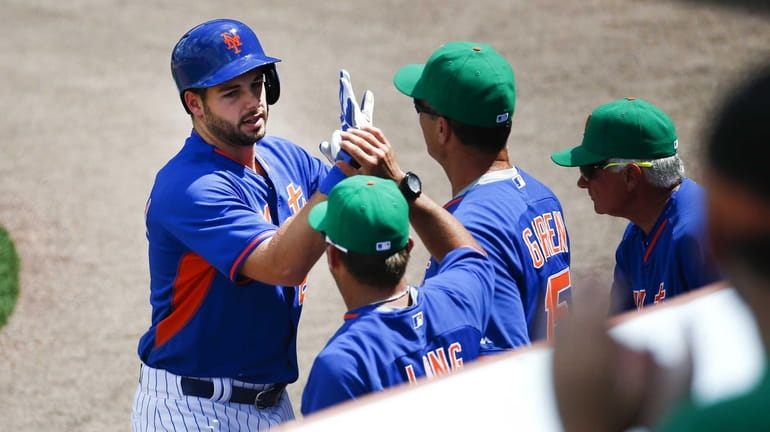 Mets catcher Kevin Plawecki, left, is greeted at the dugout...