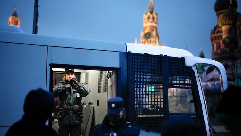 A police officer stands inside a police bus with detained...