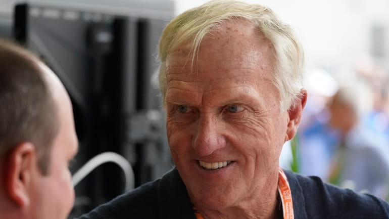 Professional golfer Greg Norman walks through the pit area during...