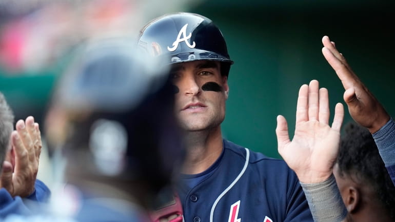 Atlanta Braves' Sam Hilliard high-fives teammates in the dugout after...