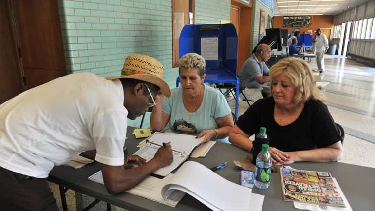 Election workers Johann Tamburello, left, and Margaret Hitchcock assist voter...