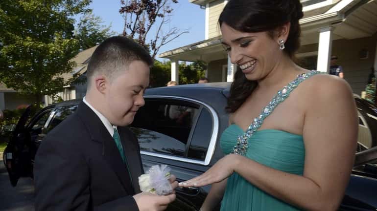 Christopher Bartley places a corsage on Brooke DiPalma's wrist as...