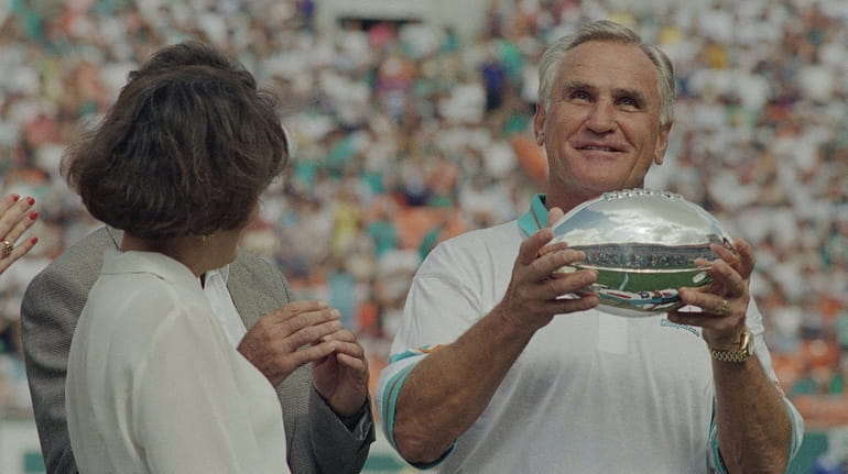 Miami Dolphins coach Don Shula holds up a silver football...
