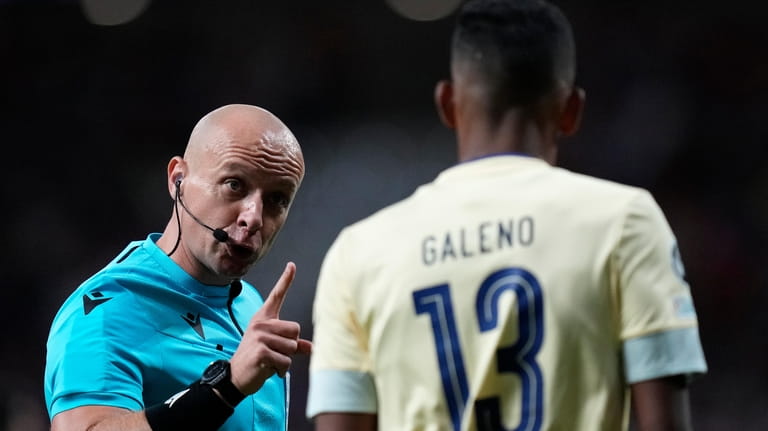 Referee Szymon Marciniak, left, talks with Porto's Galeno during the...