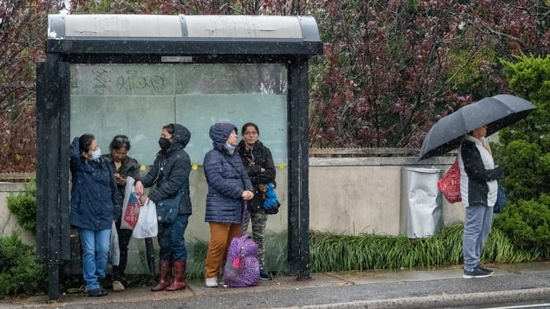 People try to stay dry as they wait for the bus...