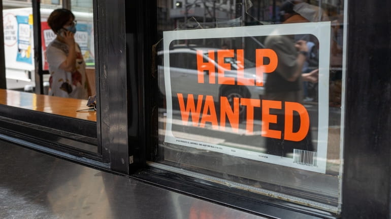 A "help wanted" sign is displayed in a window in...