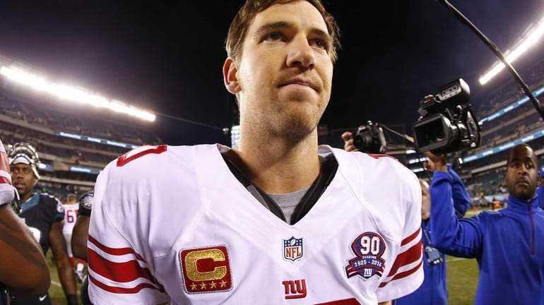 Giants quarterback Eli Manning walks off the field after being...