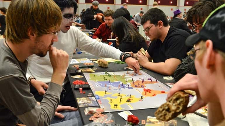 Friends play a board game called Risk Legacy at I-CON.