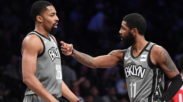 Nets guard Kyrie Irving talks to guard Spencer Dinwiddie during...