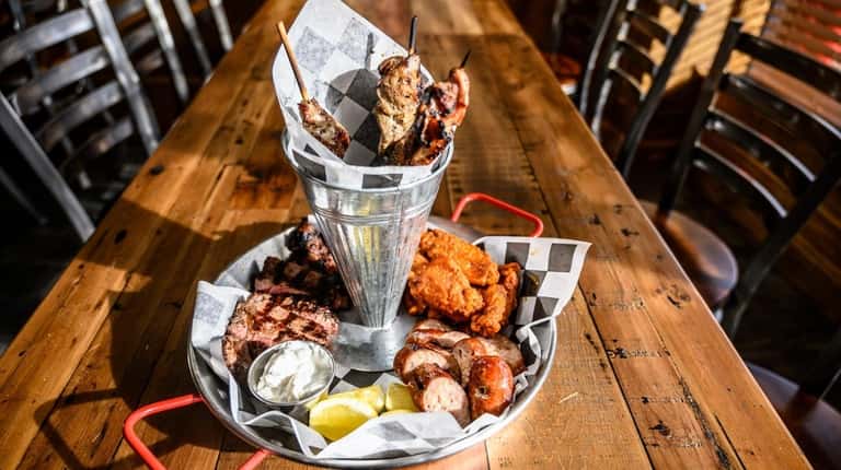 Holy Smoke's "combo feast" features wings, pork skewers, sausage and...