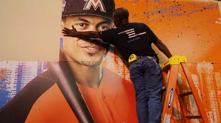 Francois Diesiul hangs a poster bearing the visage of Miami...