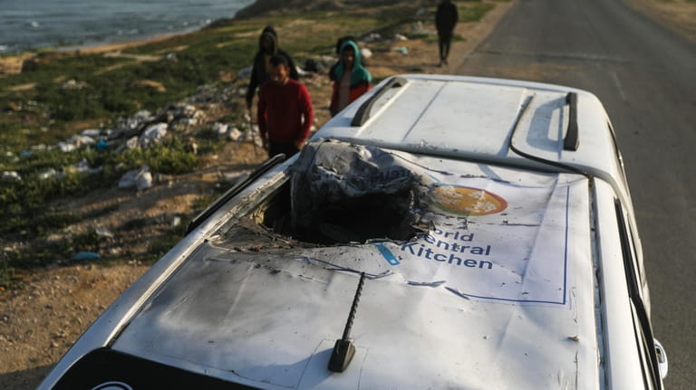 Palestinians inspect a vehicle with the logo of the World...