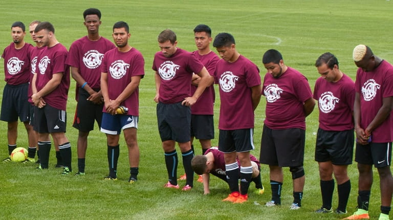 Players bow their heads in a moment of prayer at...